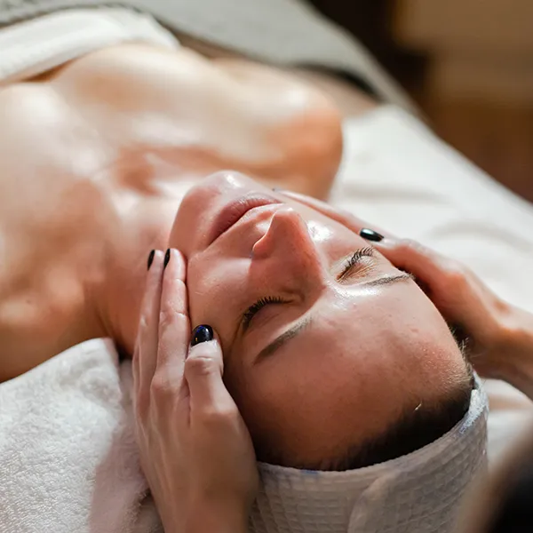 Kalon provider massages their patient's face. The patient's eyes are closed and she is relaxed.